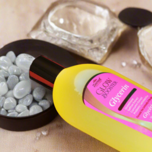 Bottle of Zeenat Glow Booster Glycerin on a surface with polished stones and a clear jar.